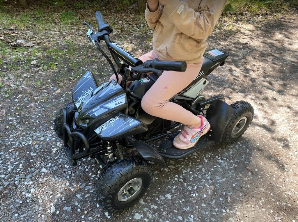 Grå-svart Nitrox Spirit ATV el-fyrhjuling för barn testkörs på en grusväg